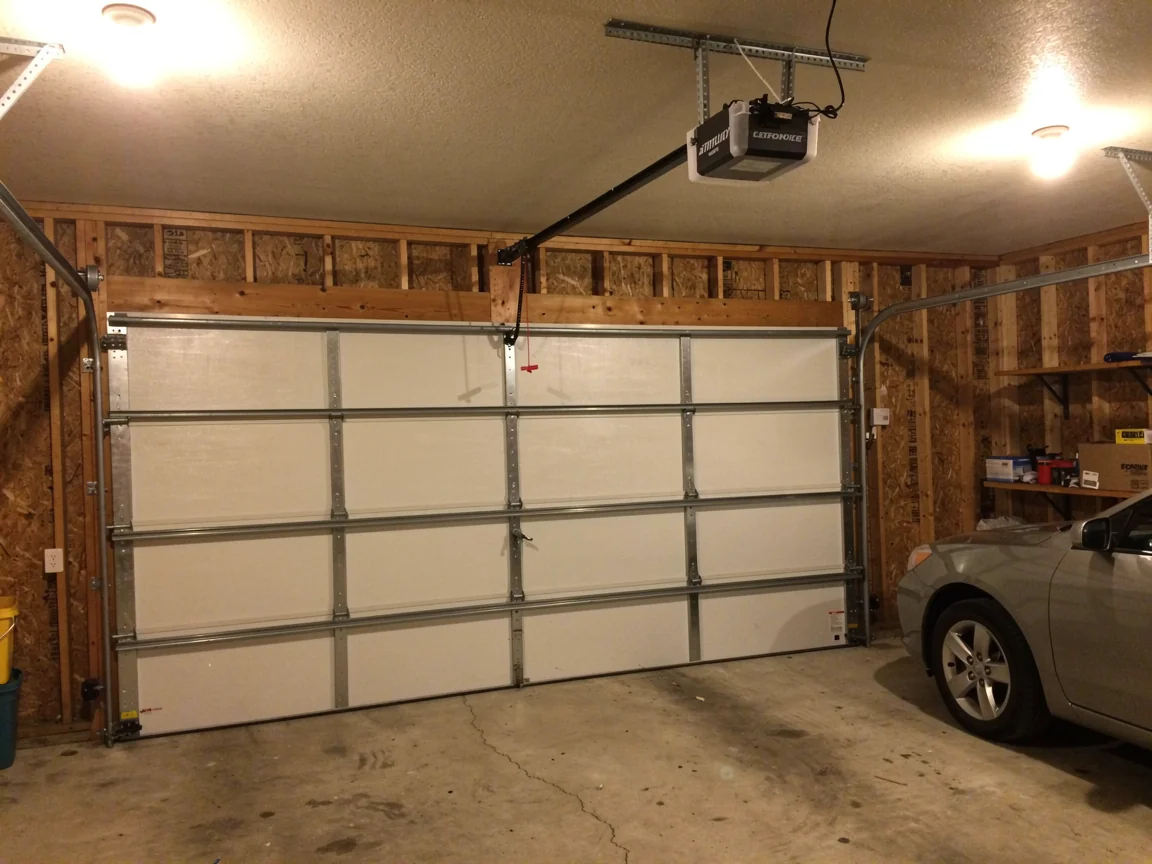 A white garage door is closed with an opener and a car visible inside.